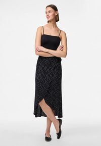 Melnā apkārtne svārki ar baltajiem punktiņiem, asimetrisks apakšmalas dizains, viegla auduma, kombinēti ar melnu bezpiedurkņu topu un baleta kurpēm.