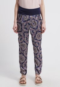 Elasticated waist trousers in navy with intricate paisley pattern in purple and green. Lightweight fabric, tapered ankles, and side pockets.