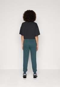 Nike Sportswear CLUB SHINE PANTS - Teplákové kalhoty - deep jungle