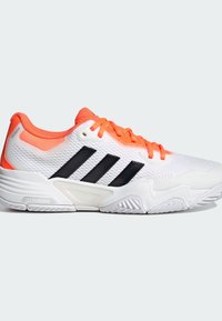 Λευκό αθλητικό παπούτσι με μαύρες ρίγες, πορτοκαλί λεπτομέρειες, επάνω μέρος από δίχτυ και υφή στη σόλα. Διαθέτει μαλακή ενδιάμεση σόλα για άνεση.