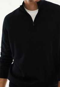 Maglione nero con zip, caratterizzato da un alto colletto, maniche lunghe e una texture morbida. Il design è semplice e aderente.