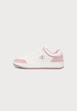 Weiße und pinke Sneaker mit niedrigem Schaft, Schnürung vorne, pinken Wildlederelementen und einem Champion-Logo an der Seite und Ferse.