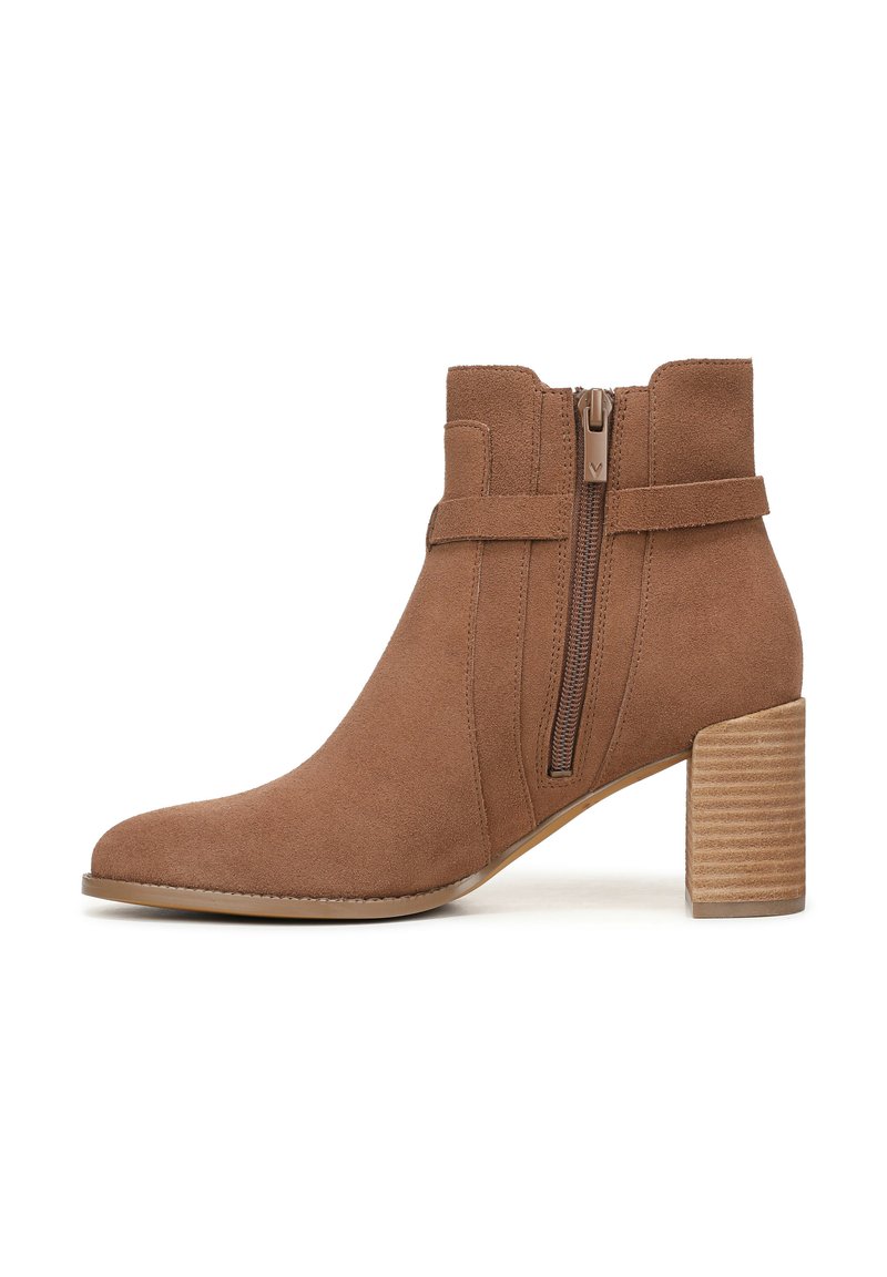 Brauner Wildleder-Stiefeletten mit spitzer Zehenform, seitlichem Reißverschluss und einem gestapelten Holzabsatz. Mit einem Riemen um den Knöchel.