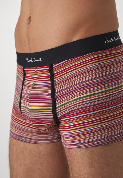 Caleçons boxers rayés multicolores en tissu doux, avec une ceinture noire arborant le logo "Paul Smith" et des accents rouges, jaunes et bleus.