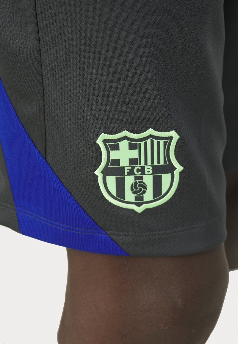 Pantalones cortos deportivos negros con un panel lateral azul y un logo del FC Barcelona en verde claro. Cuenta con una tela texturizada y transpirable.