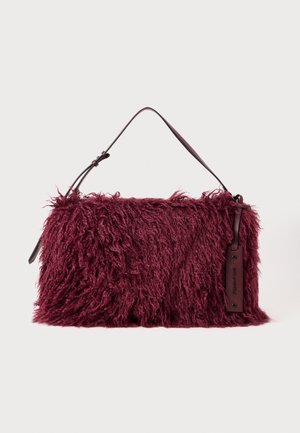 Burgundy handbag with a fluffy texture, featuring a short leather strap and a side tag for branding. Soft, shaggy material design.