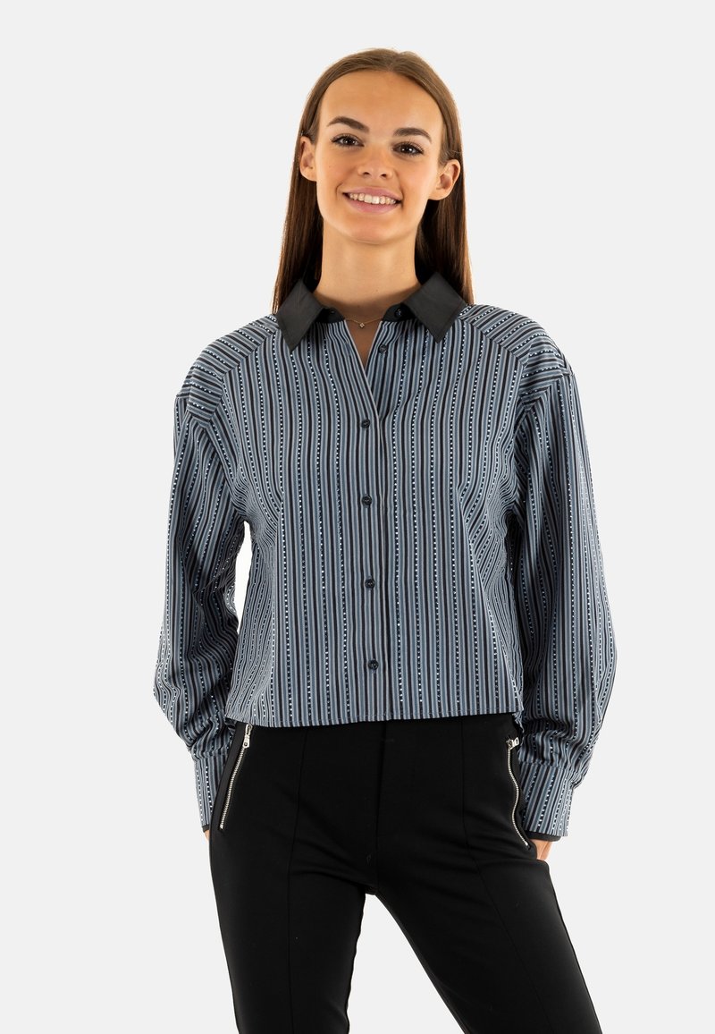 Blusa a rayas azul y blanca con cuello negro, cierre de botones en la parte delantera y mangas largas. Presenta líneas verticales y patrones sutiles.