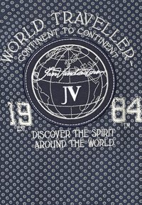 Marineblauter Stoff mit weißen Diamantmustern. Zentrales gesticktes Logo mit einer Erdkugel, dem Text "WELTREISENDER" und dem Gründungsjahr "1984."