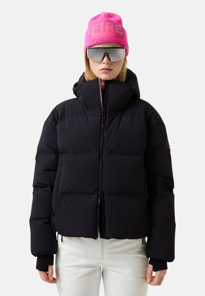 Zwarte pufferjas met een cropped ontwerp, voorzien van een hoge kraag, ritssluiting en geribde manchetten. Draagt een roze muts en een zonnebril.