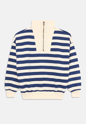 Pruhovaný pulovr s polovičním zipem; má námořnické modré a krémové horizontální pruhy, měkkou tkaninu a elastické manžety a lem.