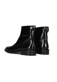 Zwarte glanzende leren enkellaarsjes met achterritsen en knoopbanden, met lage hakken en decoratieve stiksels aan de zijkanten.