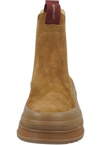 Bruine suède enkellaars met een gestructureerde bovenkant, elastische zijkanten en een beige rubberen zool. Voorzien van een bordeauxrode trekband.