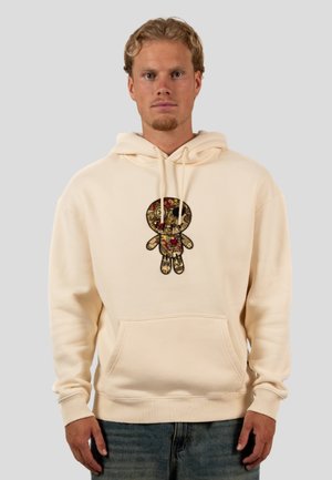 Cremefarbener Hoodie mit einem strukturierten, bestickten Puppendesign in Gold und Rot. Er verfügt über eine Vorderseite mit Tasche sowie gerippte Bündchen und Saum.