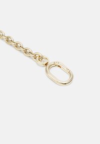 Catena in metallo dorato con grandi anelli e una robusta chiusura ovale. La superficie ha una finitura liscia e lucida. Ogni anello è interconnesso per garantire resistenza.