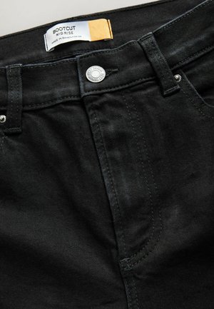 Melnas bootcut džinses ar vidēja pacēluma piegulšanu. Izgatavotas no džinsa auduma, ar pogu aizdari un divām priekšējām kabatām ar maziem šuvju akcentiem.