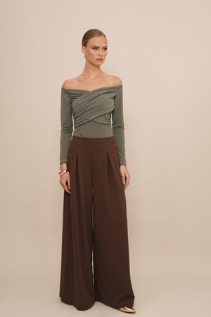 Olijfgroene off-the-shoulder top met een gedraaide ontwerp, gecombineerd met bruin wijde broek met plooien en een gladde textuur.