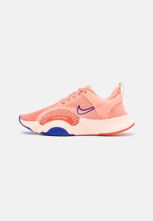 Koralowo-różowy sportowy but z siateczkową cholewką, niebieskim znakiem Nike, białą podeszwą z niebieskimi i pomarańczowymi akcentami oraz "superrep" nadrukowanym na bocznej panelu.