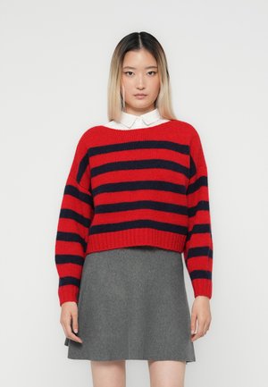 Rød og marineblå stripet genser med en cropped design, vide ermer og ribbet kant, sett sammen med et grått svingeskjørt. Glatt tekstur.