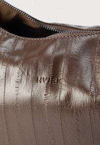 Pungă maro din piele cu dungi verticale, având logo-ul „HVISK” în relief și închidere cu fermoar. Textură netedă cu finisaj lucios.