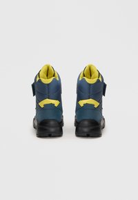 Et par blå og gule høj-top sneakers vist bagfra på en ensfarvet hvid baggrund.