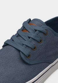 Sinine lõuendjalanõu ümmarguste metallist silmadega, paksud sobivad paelad ristkülikukujuliselt seotud ja valge kummist tallaga, millel on must triip.