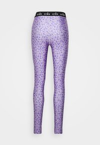 Fialové legíny s květinovým vzorem s malými bílými a žlutými květy. Elastický černý pas s opakujícím se názvem značky.