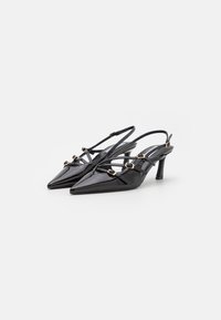 Décolleté slingback neri in vernice con punte affusolate, sottili cinturini e dettagli in metallo dorato. Tacco moderato per un po' di altezza. Texture liscia.