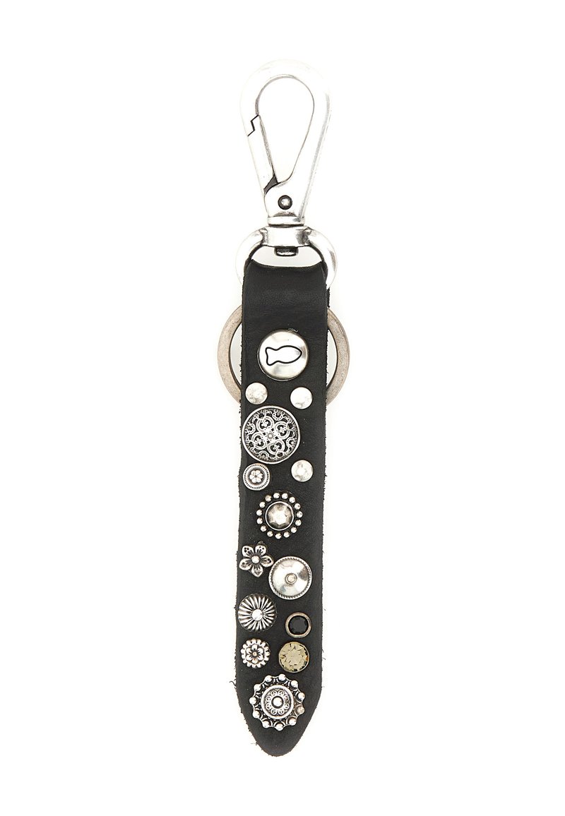 Fettuccia portachiavi in pelle nera con vari borchie e anelli decorativi in argento, attaccata a un gancio in metallo argentato e ad un portachiavi.