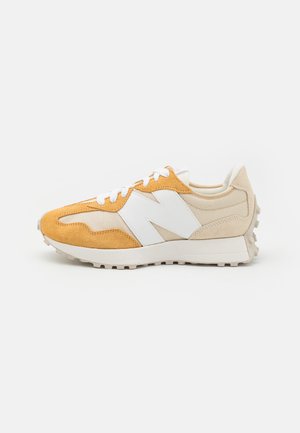 Sneaker giallo e beige con materiali in suede e rete, caratterizzati da accenti bianchi, una suola sovrapposta e lacci piatti. Vista laterale.