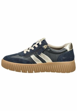 Granatowo-beżowy sneaker z grubą brązową ryflowaną podeszwą, białymi sznurowadłami, srebrnymi bocznymi paskami i małym zamkiem po boku.