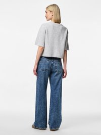 Grå cropet strikkegenser med korte ermer, kombinert med lyseblå vidbukser i denim med lyse vask og femlommersdesign.