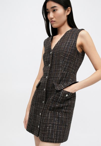Vestido de tweed marrón con escote en V, diseño sin mangas, botones en la parte delantera y dos bolsillos laterales con solapas decorativas y acentos plateados.