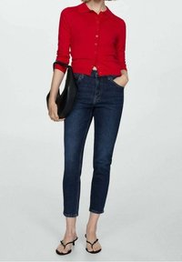 Rode button-up cardigan, donkerblauwe slim fit jeans, zwarte schoudertas en zwarte sandalen met bandjes. Eenvoudig ontwerp met een casual pasvorm.