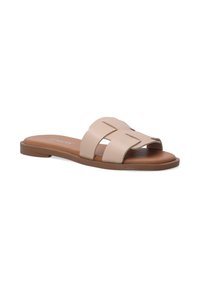 Beige leren schuif sandaal met kruislings gespen, platte bruine zool en een gladde textuur. Accenten zijn onder andere minimale stiksel details.