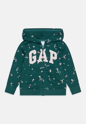 Sweat à capuche zippé vert foncé à fleurs, taille enfant, avec poches sur le devant et logo "GAP" en grandes lettres blanches sur la poitrine.