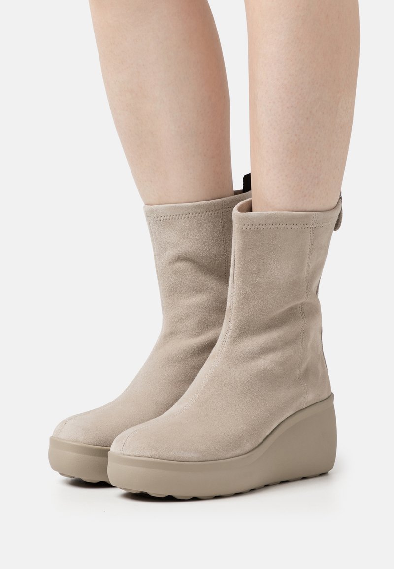 Beige Wildleder Stiefeletten mit strukturiertem Finish, runder Zehenpartie und leichtem Plateausohle, ausgestattet mit seitlichen Reißverschlüssen und einer Zuglasche.