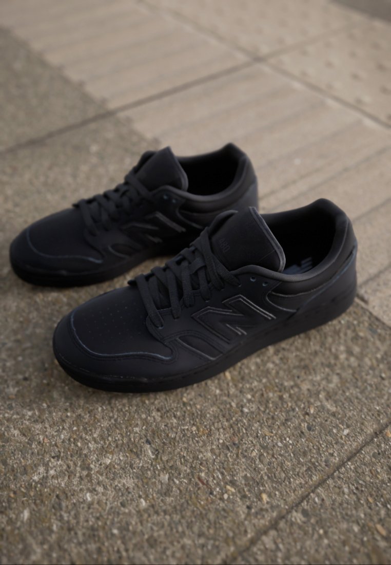Baskets noires de sport avec un dessus en cuir lisse, une pointe perforée et une semelle en caoutchouc. Présente des lacets ton sur ton et des détails en logo embossé.