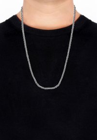 Silberne Kettenhalskette mit miteinander verbundenen ovalen Formen, liegend auf einem schwarzen Hemd. Das Design ist schlank mit einer polierten Oberfläche.