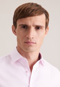 Camicia rosa chiaro con bottoni, tessuto strutturato, colletto classico e due bottoni al collo. Superficie liscia, design aderente.