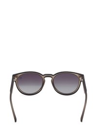 Kulaté sluneční brýle s průhledným šedým a černým rámem. Gradientní tmavé čočky s jemnými stříbrnými akcenty na kloubu.