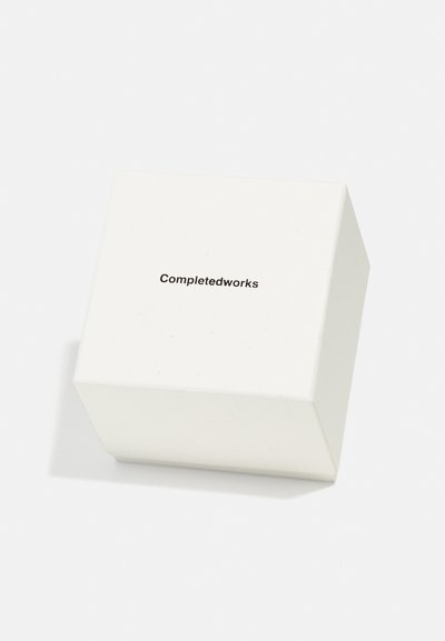 Valge ruudu kujuline karp sileda tekstuuriga, mille pealmisel osal on lihtne must kiri "Completedworks".