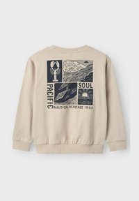 Sudadera beige con puños y dobladillo acanalados. El diseño gráfico en la parte posterior presenta motivos náuticos, incluyendo una langosta y olas en azul oscuro.