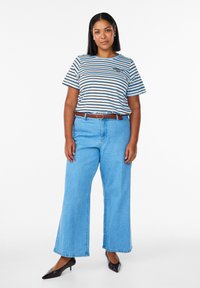 Triibuline T-särk siniste, pruunide ja valgete triipudega; helesinised laiade säärega teksapüksid; pruun vöö; mustad teravnurgaga kontsakingad; pehmed tekstuurid.