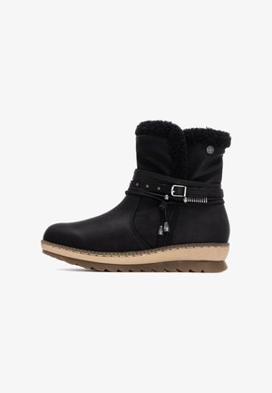 Botín de cuero negro con cuello de pelo sintético, correa decorativa, pequeños acentos metálicos y suela de goma texturizada.