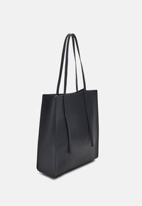 Svart rektangulär tote-väska med långa tunna handtag, slät textur och minimalistisk design på en enfärgad bakgrund.