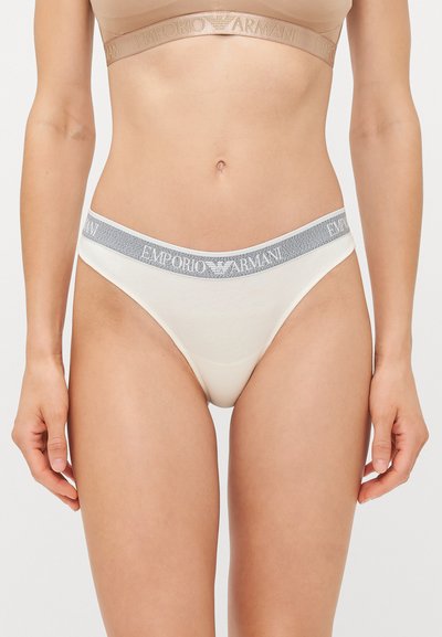 Fehér pamut tangabugyi puha, elasztikus szürke derékpánttal, amelyen az "Emporio Armani" logó látható. A dizájn minimalista, további minták nélkül.
