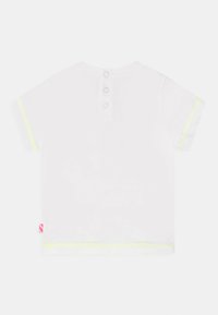 Camisa branca de manga curta com três botões nas costas, costura amarela contrastante nas mangas e um pequeno rótulo rosa na bainha.