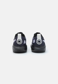 Des baskets noires et bleu marine avec une tige synthétique lisse, des accents blancs au niveau du talon et des détails de logo. Semelle texturée pour une meilleure adhérence et un confort optimal.