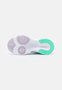 Suola di sneaker Nike bianca con motivi circolari di lavanda e un'impugnatura a tallone curva verde, marchiata "SuperRep" vicino al centro.