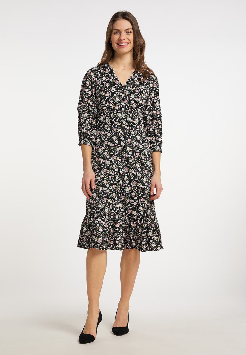 Rochie neagră cu imprimeu floral, cu decolteu în V, mâneci trei sferturi și tiv volanat. Construită dintr-un material ușor, cu modele florale roz și albe.